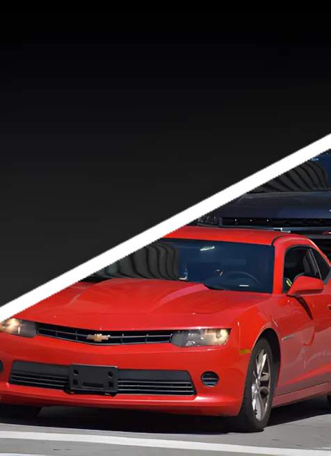 A red Chevrolet Camaro driving on a road, with the top half of the image featuring a dark, diagonal gradient background.