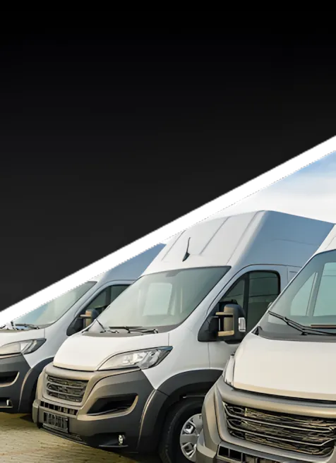 Several white delivery vans are parked in a row outdoors, with a diagonal black gradient partially covering the top portion of the image.