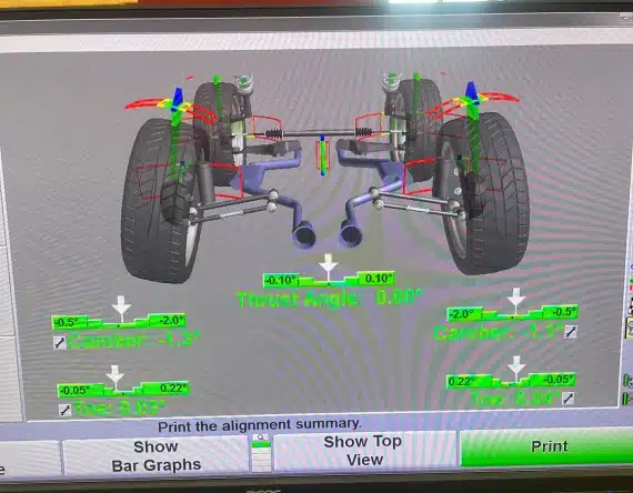 A vehicle wheel alignment screen displays a digital diagram of the suspension, two large rear tires, alignment angles, and measurements for camber, toe, and thrust angle, with print and display options below.